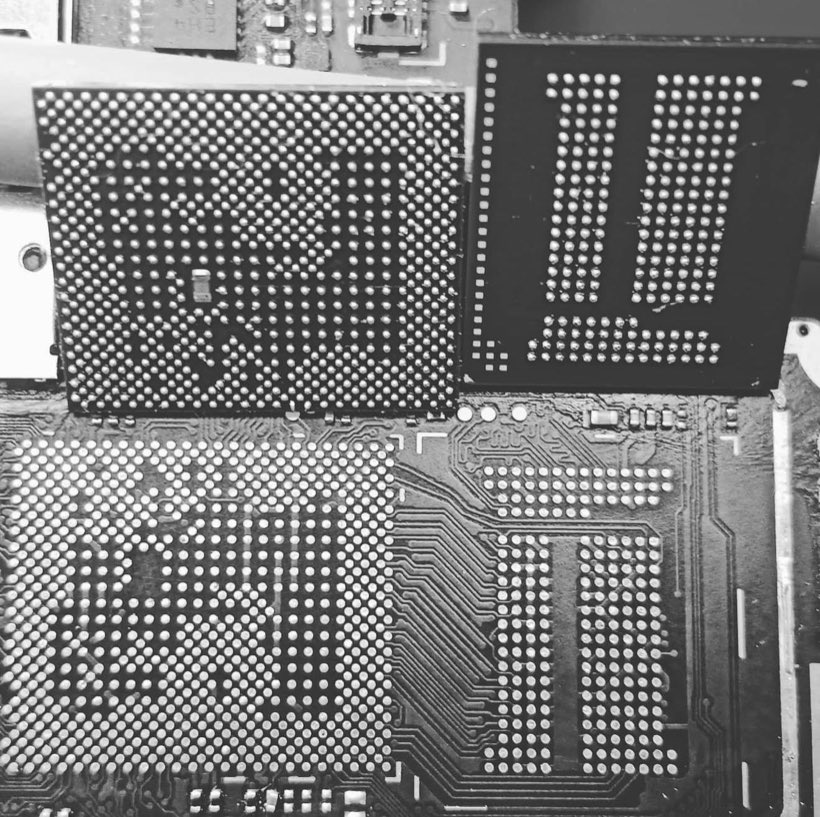 Black and white macro of reballed BGA chips beside the bare solder pads on a phone motherboard
