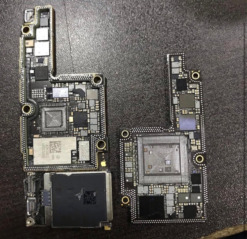 Two iPhone logic boards with their shields and processors removed, laid out on the bench