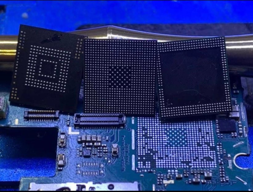 Three BGA chips lifted from a phone motherboard, resting on the blue-lit board they came from