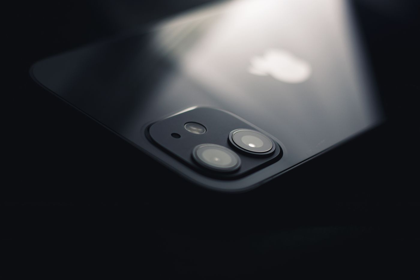 Back glass and camera module of a dark iPhone catching a streak of studio light